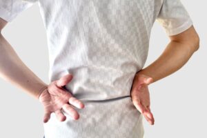 反り腰による腰痛で腰の真ん中を押さえる女性